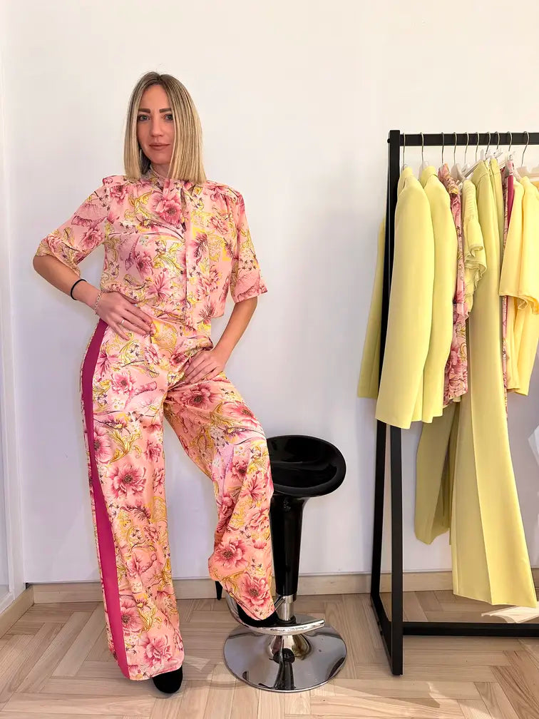 Pantalone fantasia floreale rosa e gialla con banda laterale fuxia indossata da donna – look elegante e primaverile