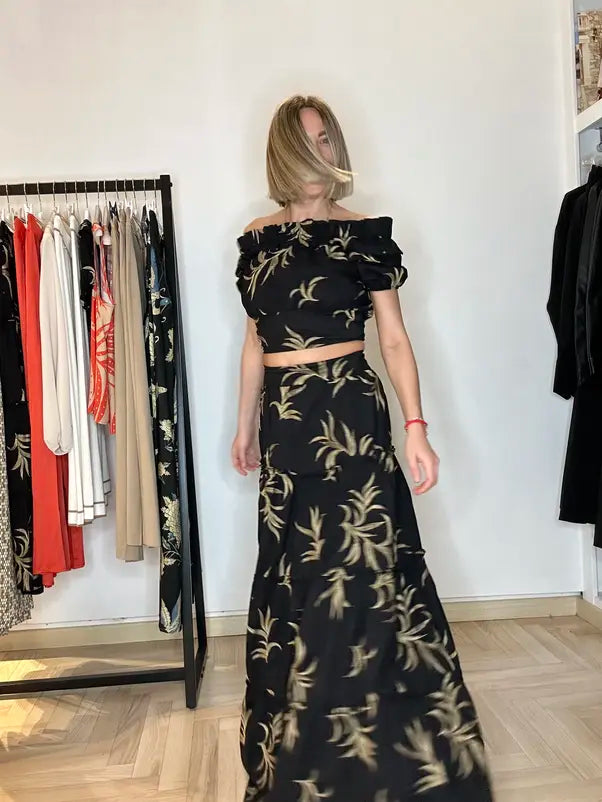 modella bionda che indossa un top nero di cotone corto abbinato con la gonna lunga della stessa fantasia