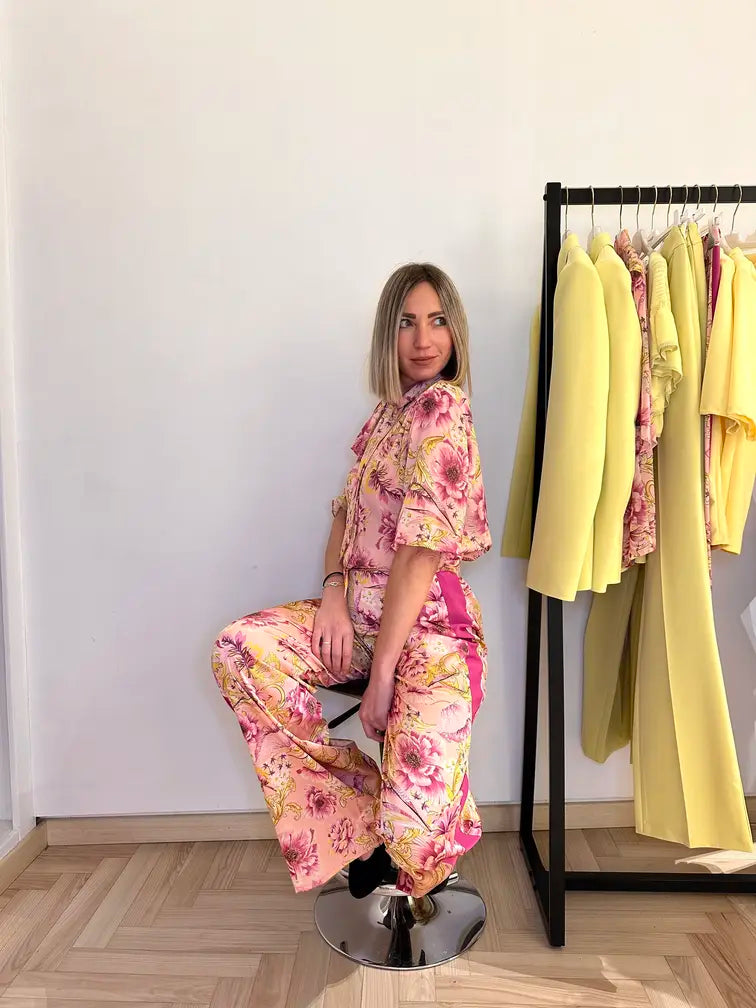 Pantalone rosa a fiori con banda laterale, un capo perfetto per essere abbinato con la sua blusa stessa fantasia a manica corta e fiocco frontale