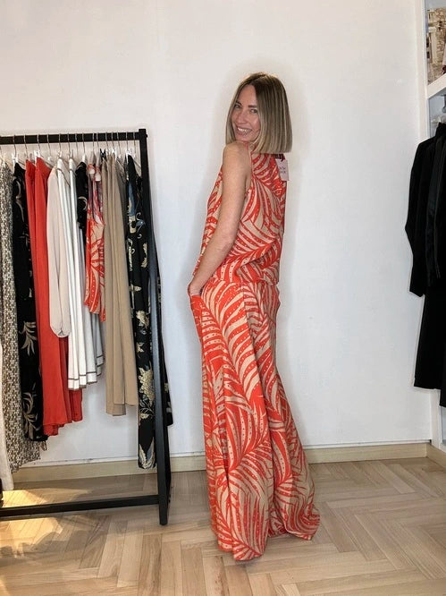 modella bionda che indossa un pantalone a palazzo in fantasia tropicale nel color corallo e corda