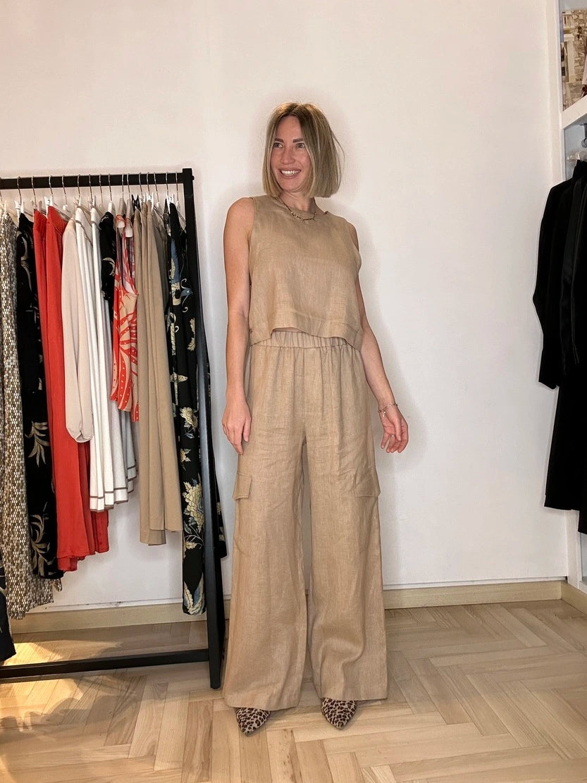 Modella che indossa un top di lino nel colore beige, scollo tondo. Perfetto per una giornata calda a Firenze d'estate