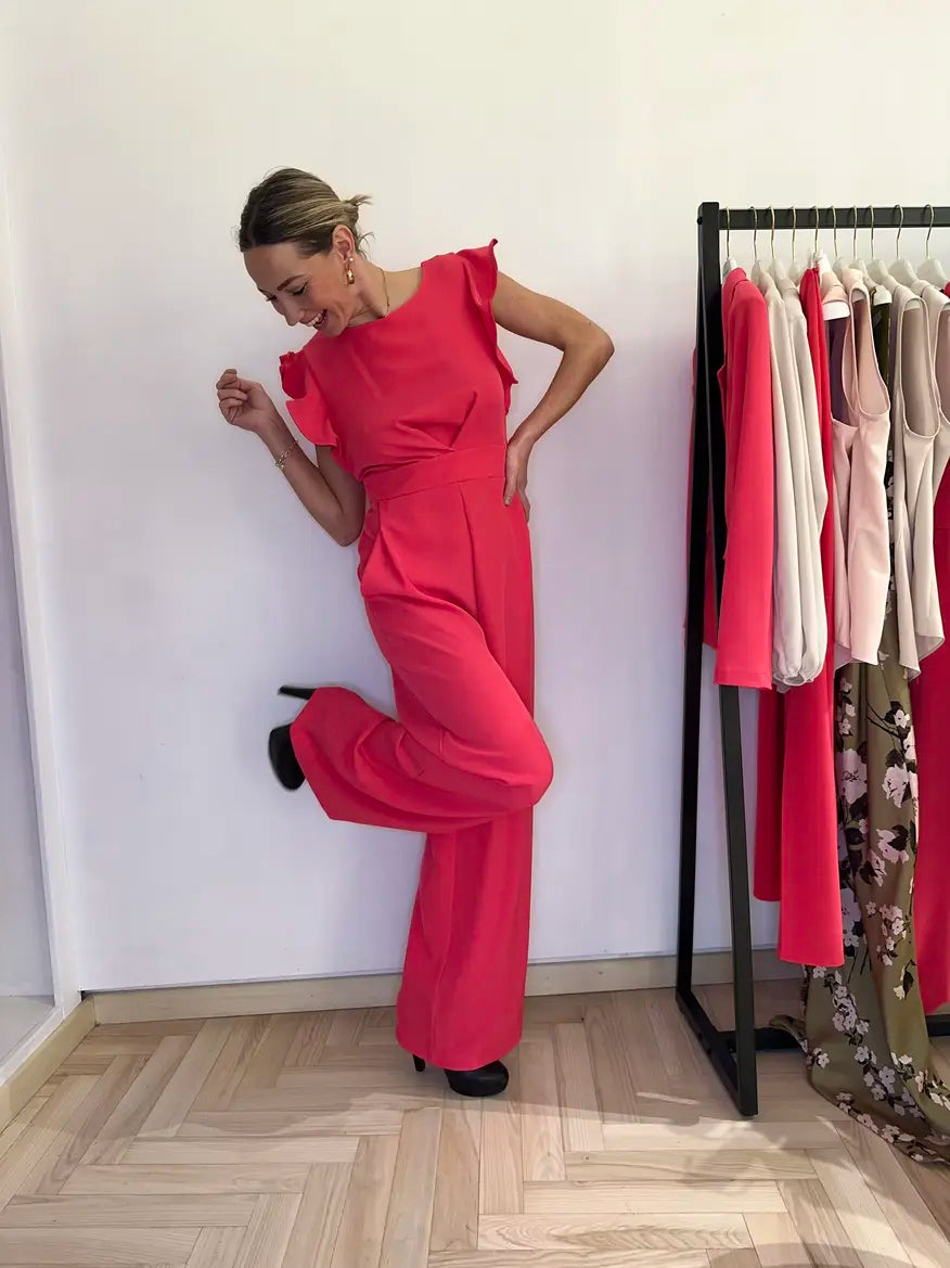 Tuta elegante claset color fuxia con maniche a rouche, indossato da modella sorridente in negozio