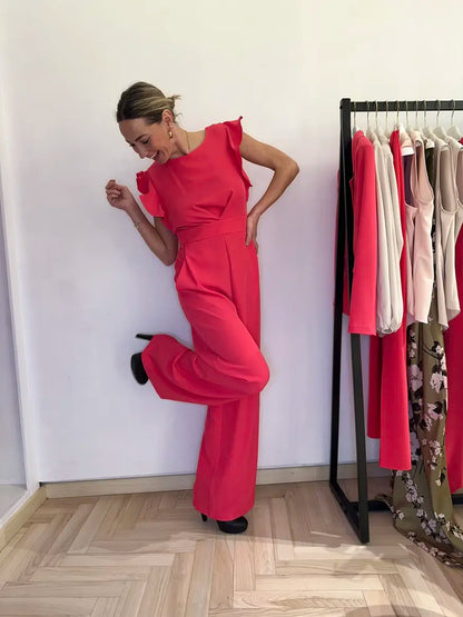 Tuta elegante claset color fuxia con maniche a rouche, indossato da modella sorridente in negozio