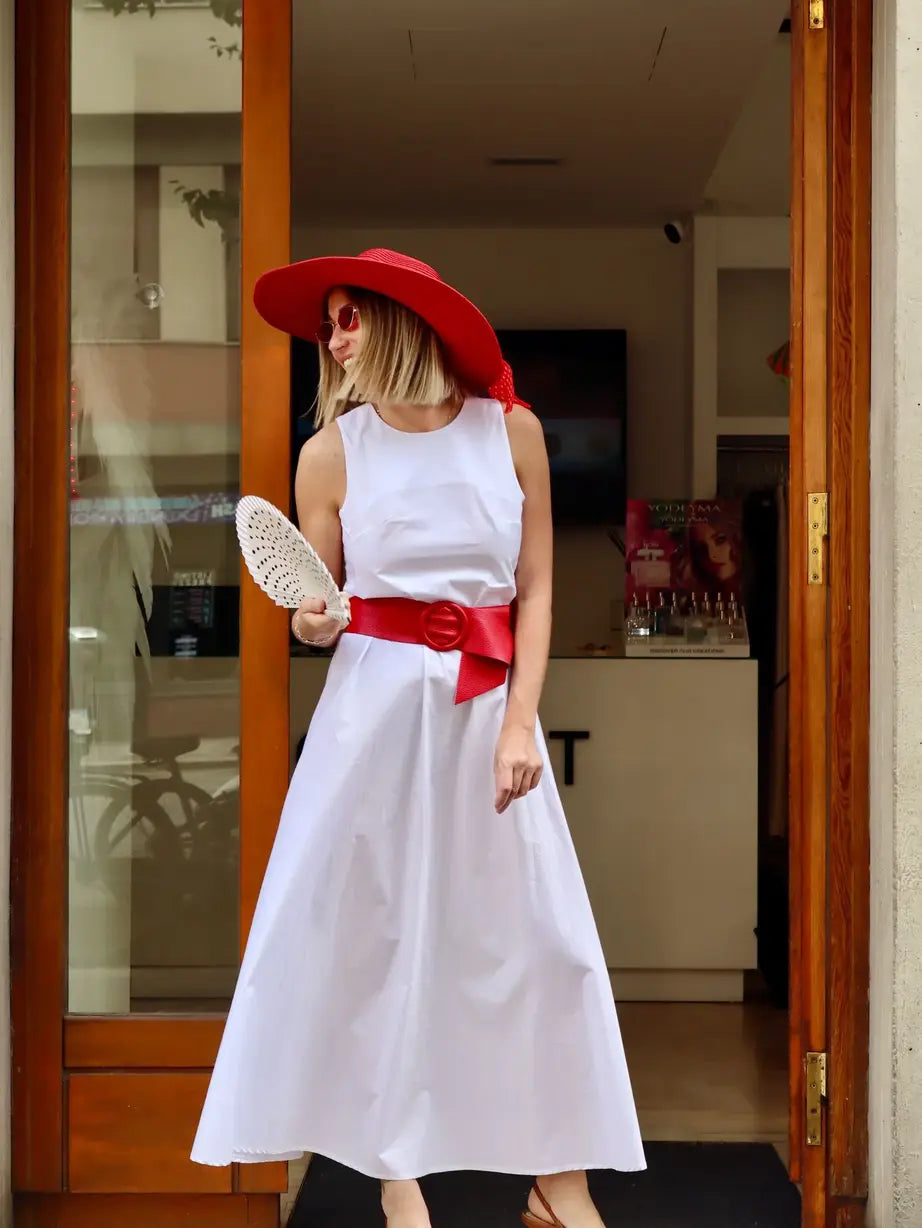modella che indossa davanti al negozio claset firenze un abito lungo bianco di cotone abbinato con un cappello rosso e cintura rossa 