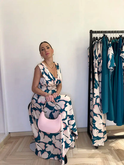 Abito lungo elegante Claset fantasia floreale beige e verde reale, con scollo a V e gonna ampia, indossato da modella con borsa rosa cipria in boutique