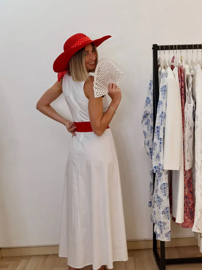 modella che indossa un abito bianco ottico di cotone con un cappello rosso cintura rossa e ventaglio bianco a pois