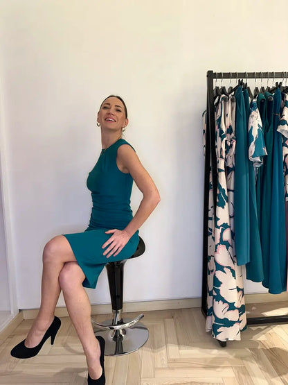 Abito verde smeraldo elegante Claset indossato da modella in boutique, taglio aderente con drappeggio laterale, stile raffinato per cerimonie o eventi