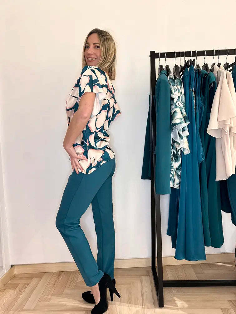 Donna indossa una blusa effetto seta a fantasia floreale sui toni del rosa e verde reale,  – outfit Claset primavera estate.