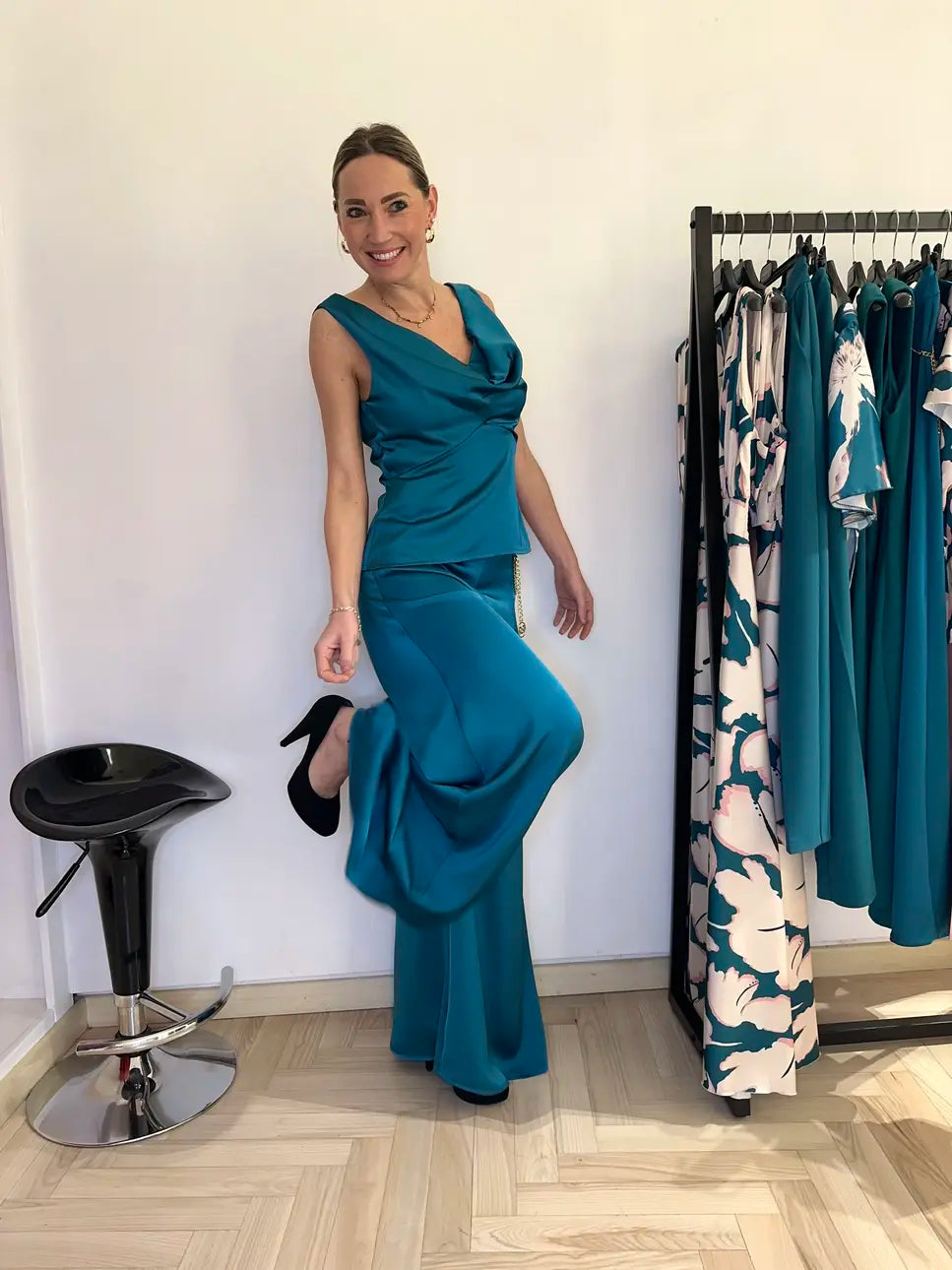 Modella sorridente indossa completo elegante Claset in raso verde reale con top scollo morbido e pantalone a palazzo, look cerimonia raffinato