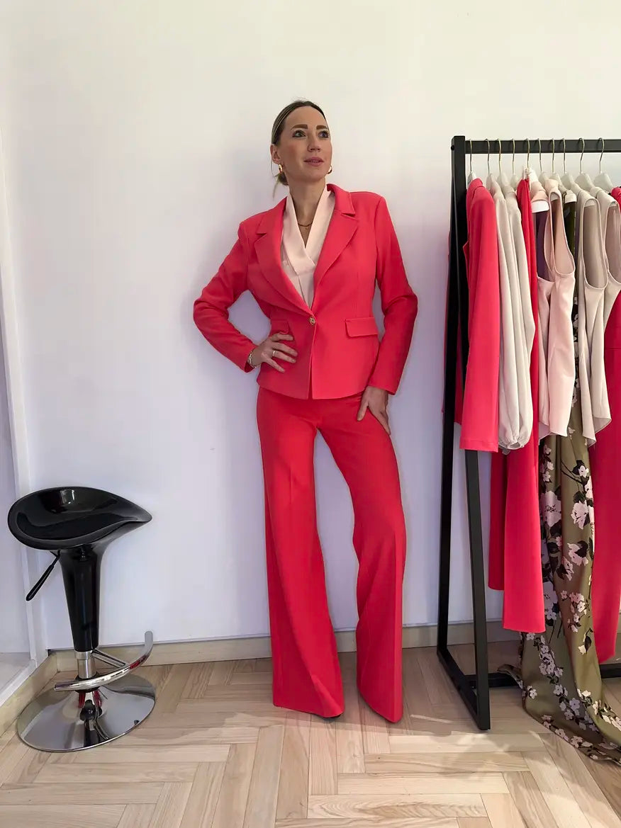 Modella sorridente indossa una blusa con scollo a V rosa chiaro abbinato con un tailleur fuxia perfetto per una cerimonia o laurea