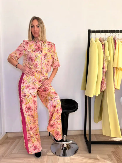 Pantalone fantasia floreale rosa e gialla con banda laterale fuxia indossata da donna – look elegante e primaverile