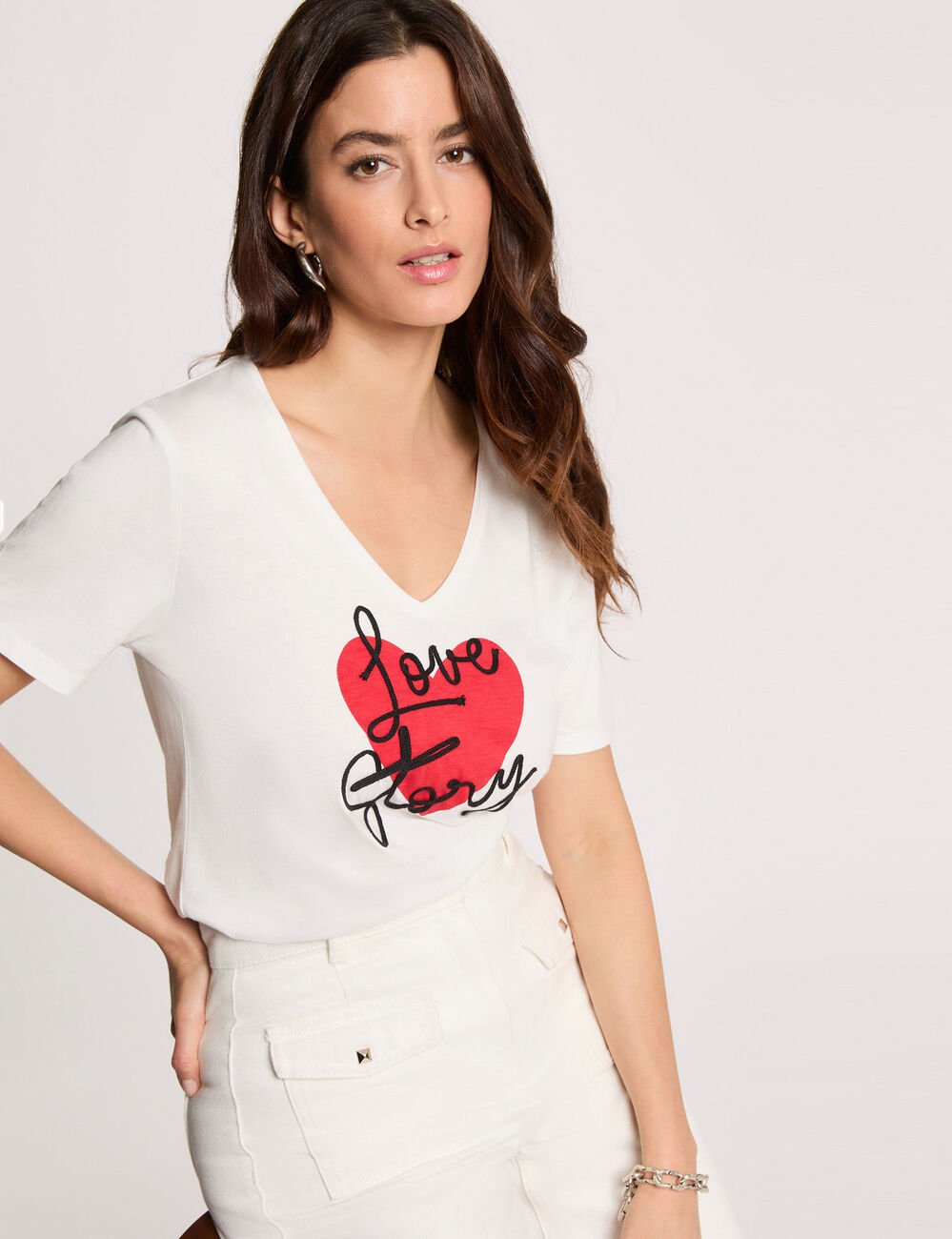 modella che indossa una morbida t-shirt di cotone bianca a maniche corte con il cuore rosso frontale e la scritta love story