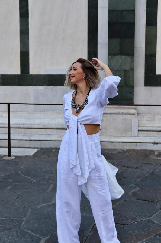 modella che indossa un top di lino naturale bianco ottico con nodo frontale e manica 3/4 a sbuffo