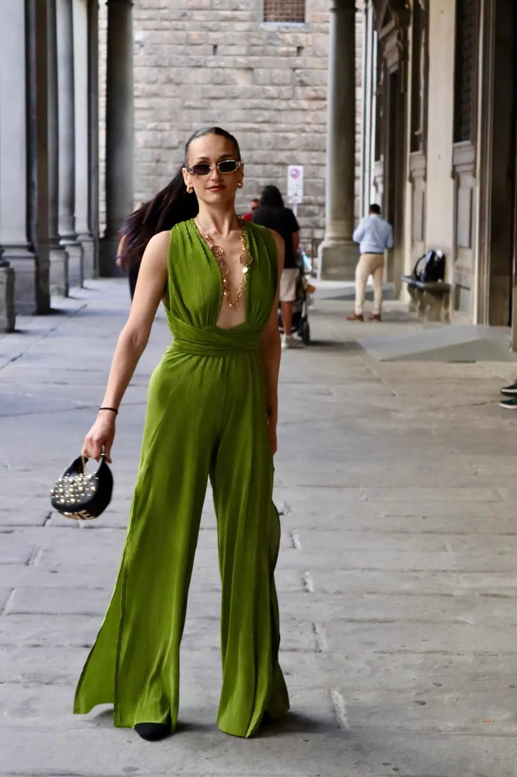 modella mora che indossa una tuta plisse' color lime in centro a firenze sotto i portici degli uffizi